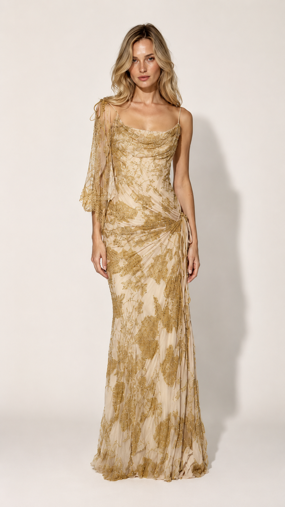 Front view of champagne one-shoulder fitted evening gown with sheer draped sleeve