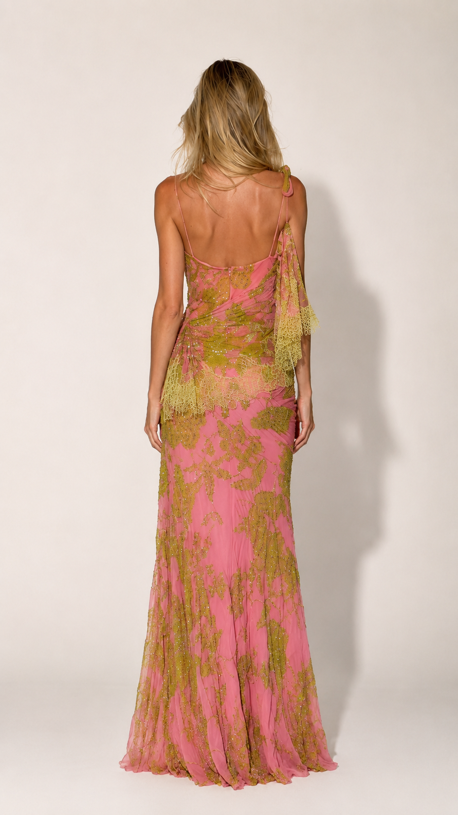 Back view of pink one-shoulder formal gown with sheer draped sleeve and fitted shape